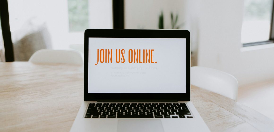 a photo of an open laptop on a table showing "Join Us" displayed
