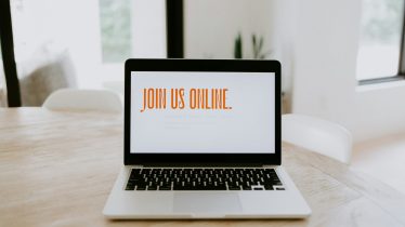 a photo of an open laptop on a table showing "Join Us" displayed